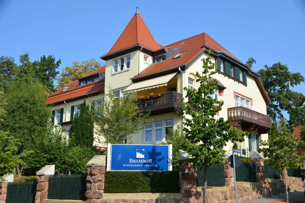 Villa Brambor in Döbeln: Gründerzeitvilla mit rotem Spitzdach, Balkonen und Brambor-Schild im Grünen