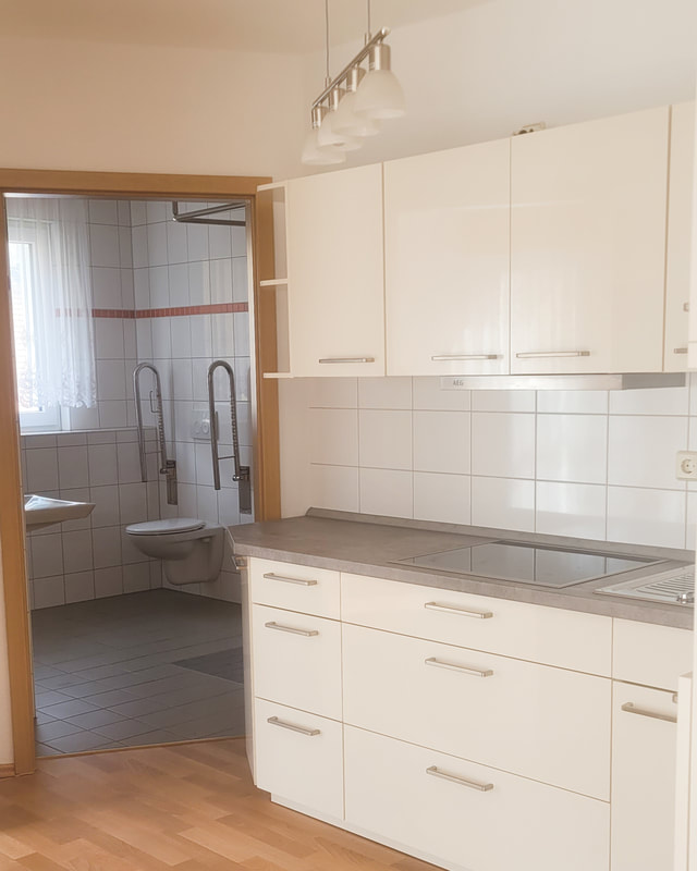 Helle Einbauküche in einer Wohnung in Ostrau mit Blick ins Bad