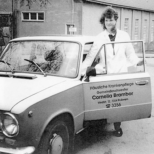 Schwarz-Weiß-Foto von 1993: Cornelia Brambor an der offenen Tür ihres Lada mit der Aufschrift „Häusliche Krankenpflege Gemeindeschwester Cornelia Brambor“