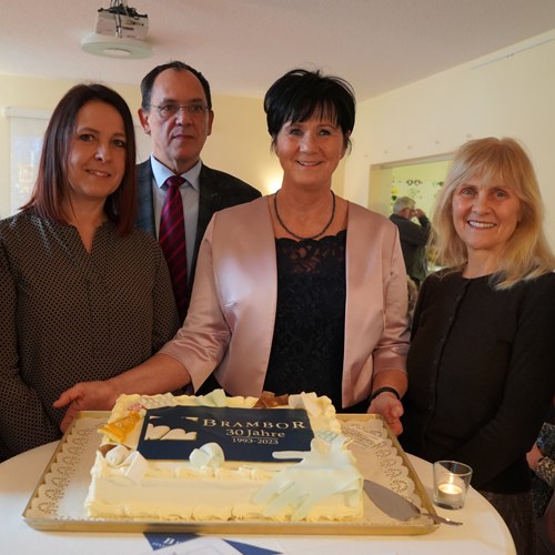 Vier Personen mit einer Jubiläumstorte zu 30 Jahren Brambor