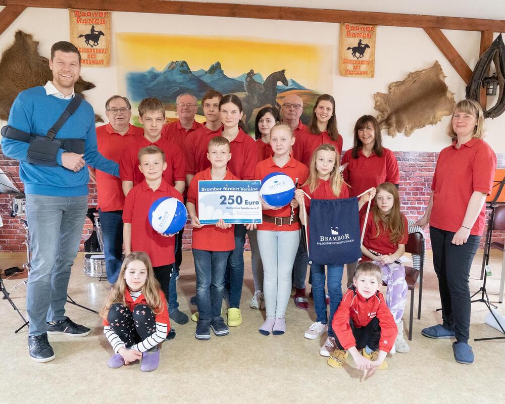 Kinder der Roßweiner Spielleute in roten Shirts mit einem Spendenscheck und ihren Instrumenten