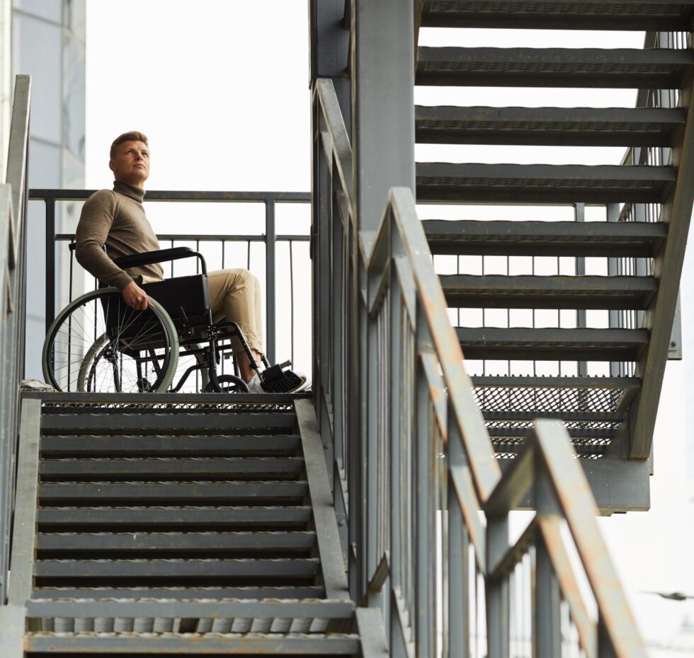 Mann im Rollstuhl am oberen Ende einer Metalltreppe