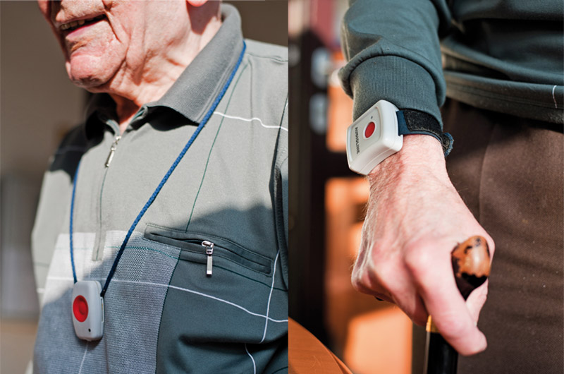 Notrufknopf an der Halskette und als Armband am Handgelenk eines Seniors mit Gehstock
