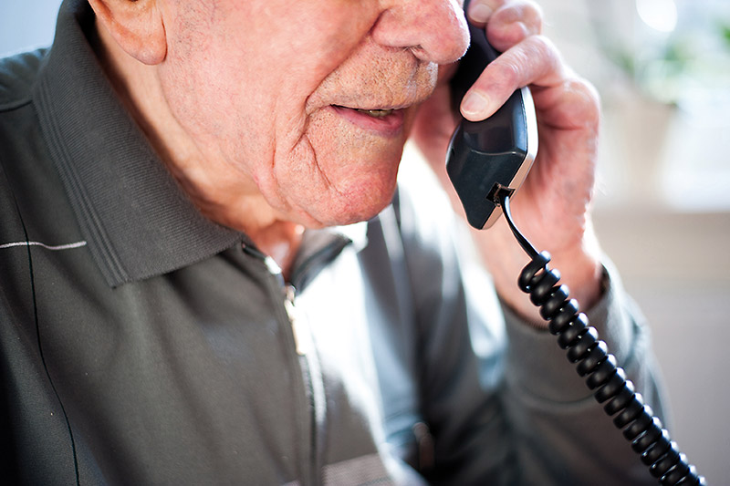 Älterer Herr telefoniert mit einem Festnetztelefon