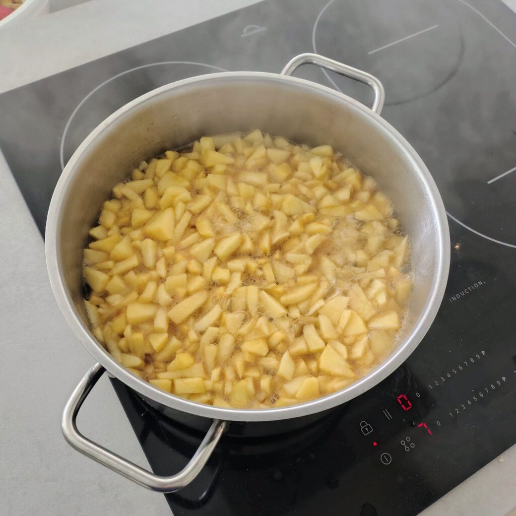 Apfelstücke köcheln in einem Topf auf dem Induktionsherd