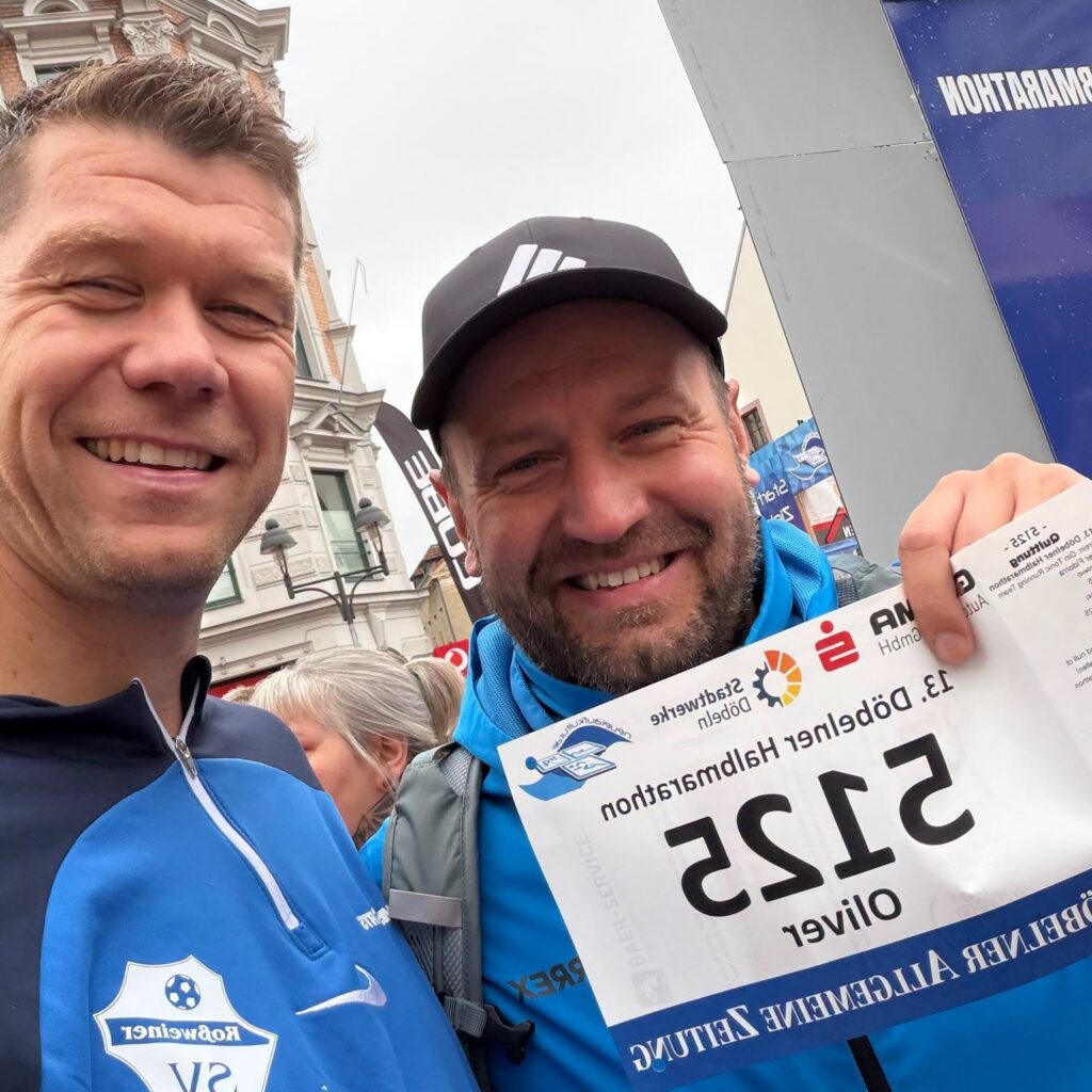 Zwei Männer machen ein Selfie, einer trägt ein Trikot des Roßweiner SV, der andere hält seine Startnummer des 13. Döbelner Halbmarathons