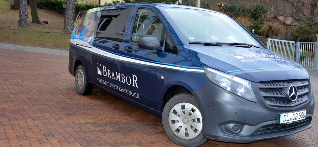 Dunkelblauer Kleinbus des Brambor-Fahrdienstes auf einem gepflasterten Hof