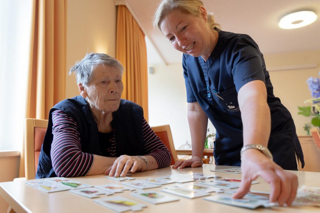 Pflegerin legt mit einer Seniorin in der Tagespflege Roßwein Memory-Karten auf dem Tisch aus