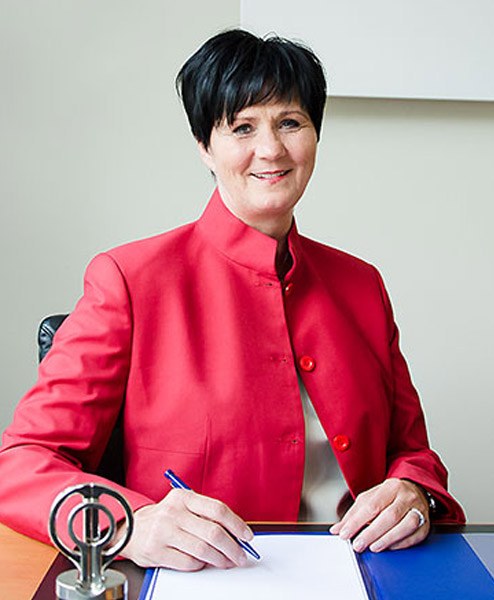 Porträt von Cornelia Brambor am Schreibtisch, in rotem Blazer